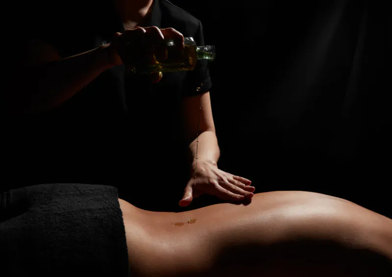 Therapist pouring oil from bottle and massaging woman's lower back during ESPA treatment at Fairmont St Andrews