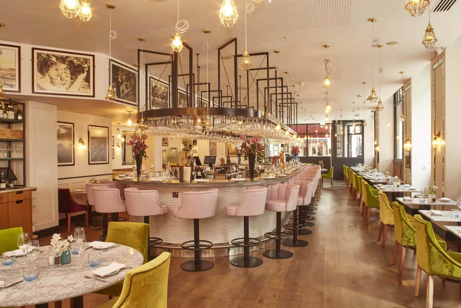 Elegant 28-50 Oxford Circus restaurant interior with pink bar stools, green chairs, pendant lights, and wine glasses.