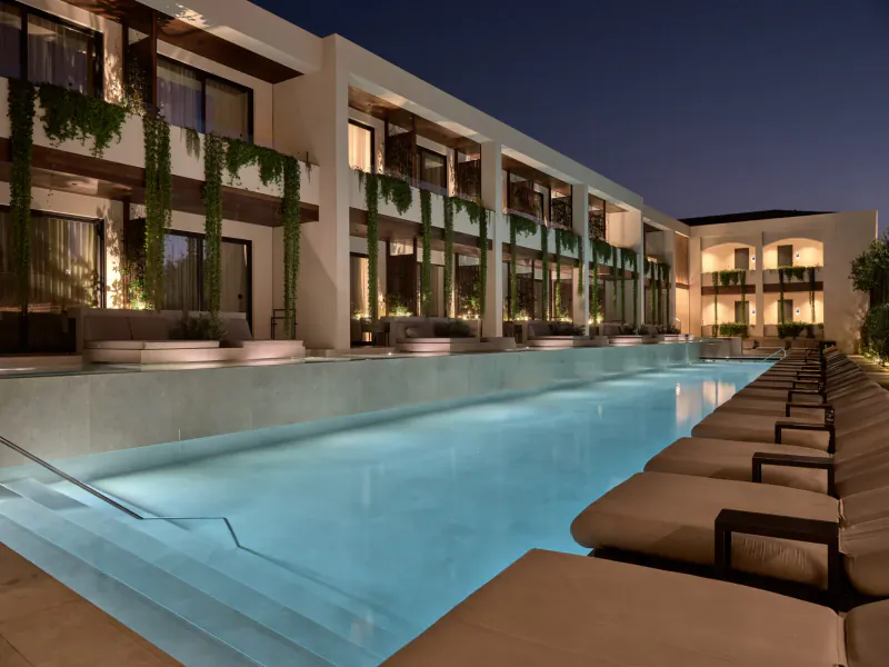 Night view of Contessina Hotel's infinity pool with loungers, modern white buildings, and greenery in Tsilivi, Zakynthos.