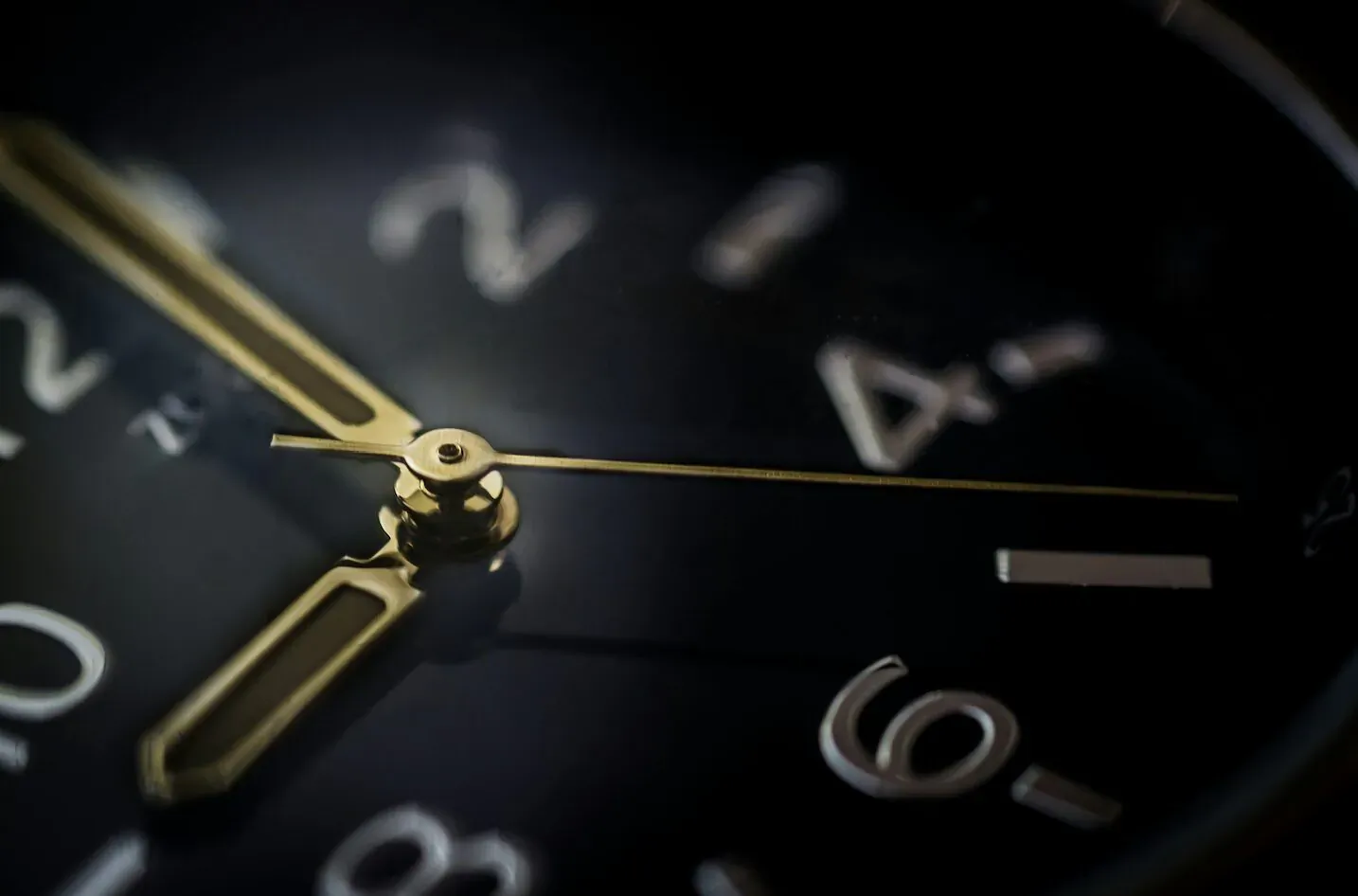 Close-up of luxury gold watch face showing time 10:20 on black dial, blurred background