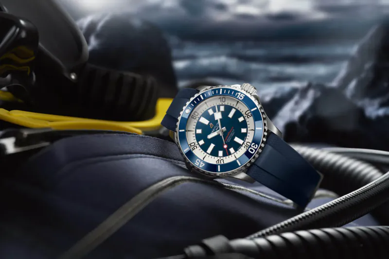 Tudor Superocean dive watch with navy blue dial and bezel on blue strap, on scuba gear in underwater scene