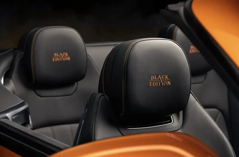 Close-up of black leather Bentley seats with orange 'Black Edition' embroidery, orange interior accents.