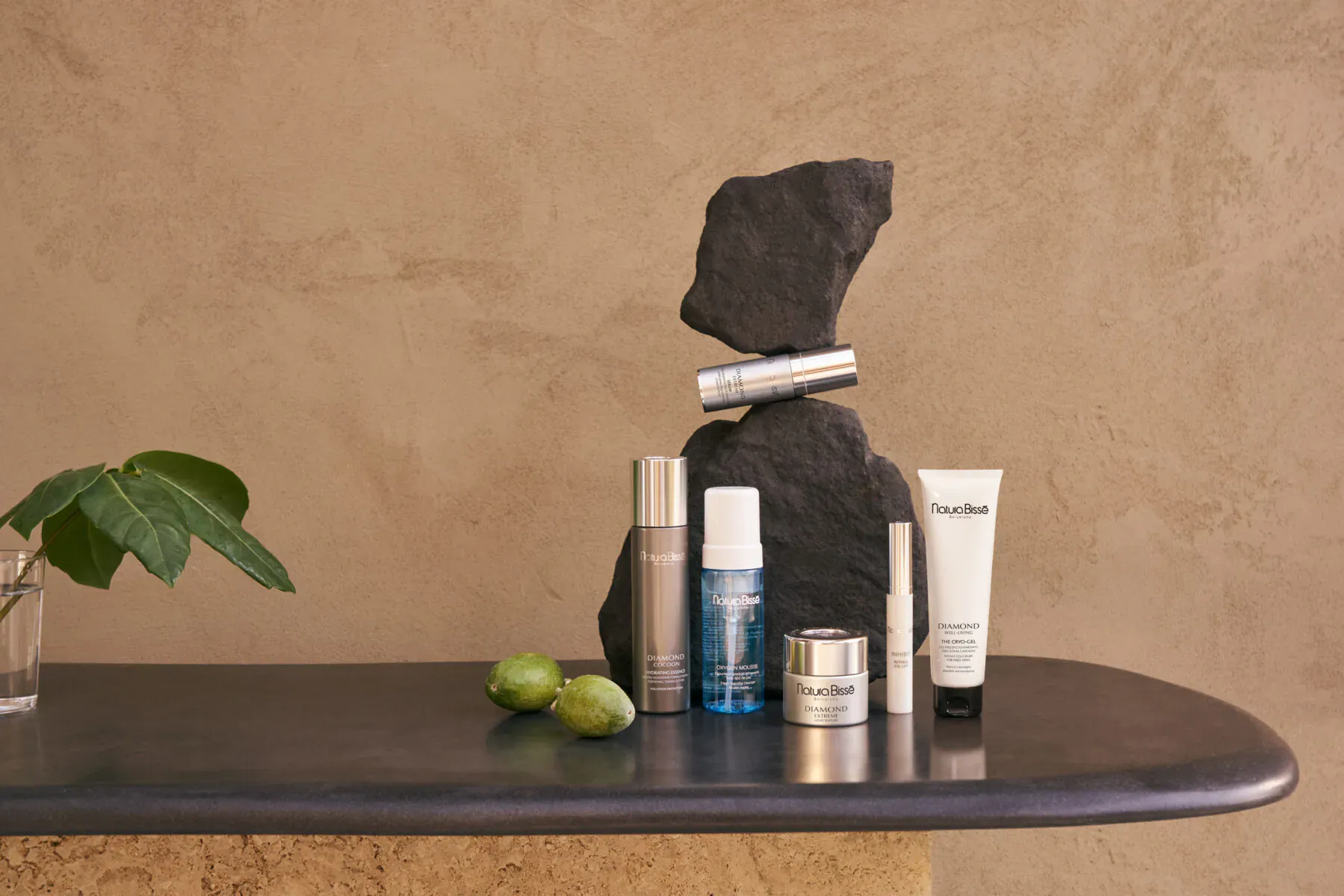 Natura Bissé men's skincare products on black table with lime slices, green leaf, and balancing black rock
