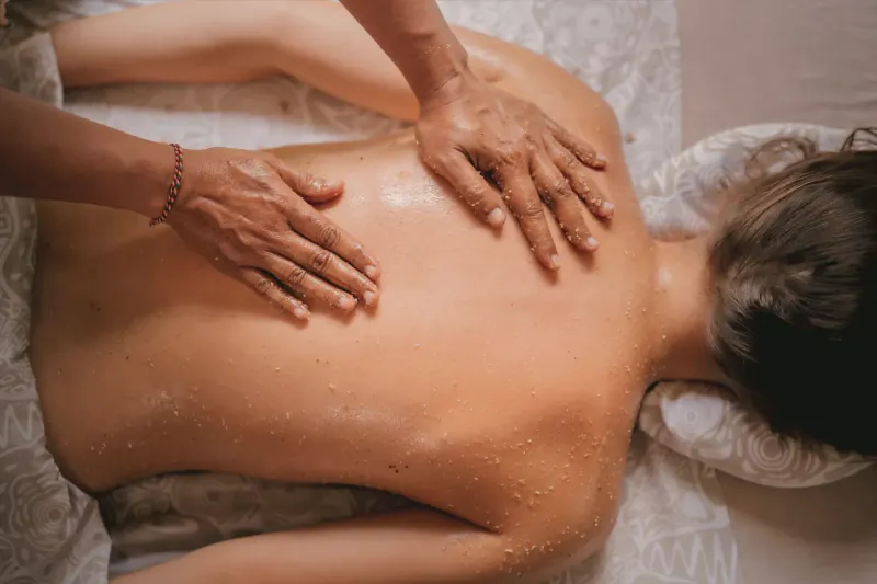 Therapist massaging the back of a woman lying face down on a spa table at Spring Spa Bali, with oil and towel.