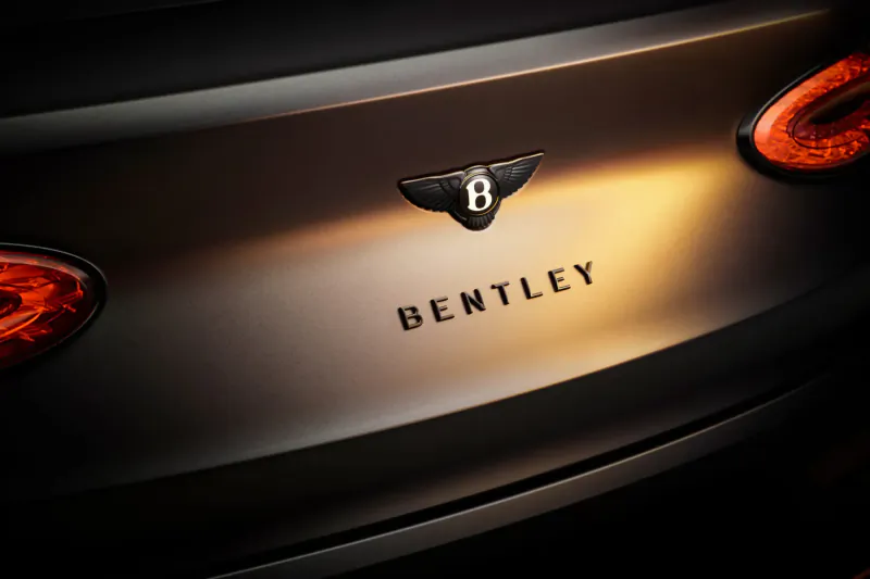 Rear view of black Bentley Black Edition with glowing red taillights, winged emblem, and 'BENTLEY' text.