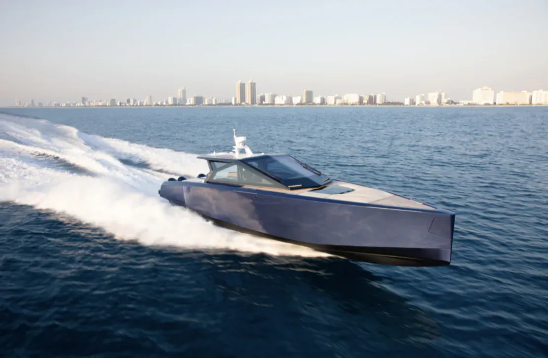 Sleek dark blue wallypower58X yacht speeding on sea with Palm Beach skyline in background.