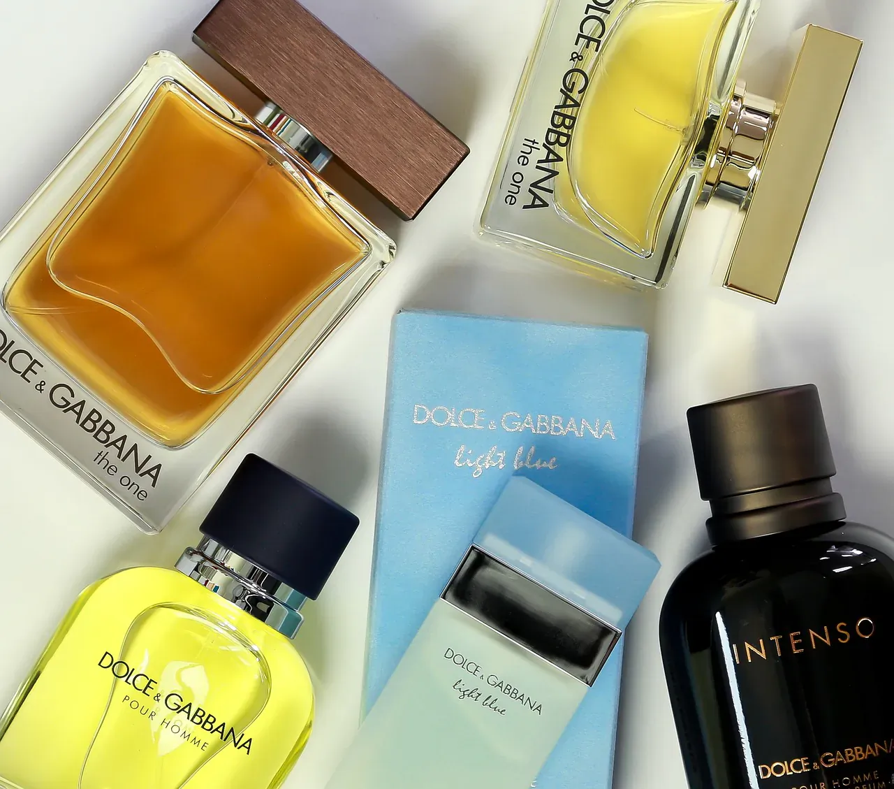 Dolce & Gabbana perfumes: Light Blue, The One, Light Blue Eau Intense, and Intenso bottles on white surface.