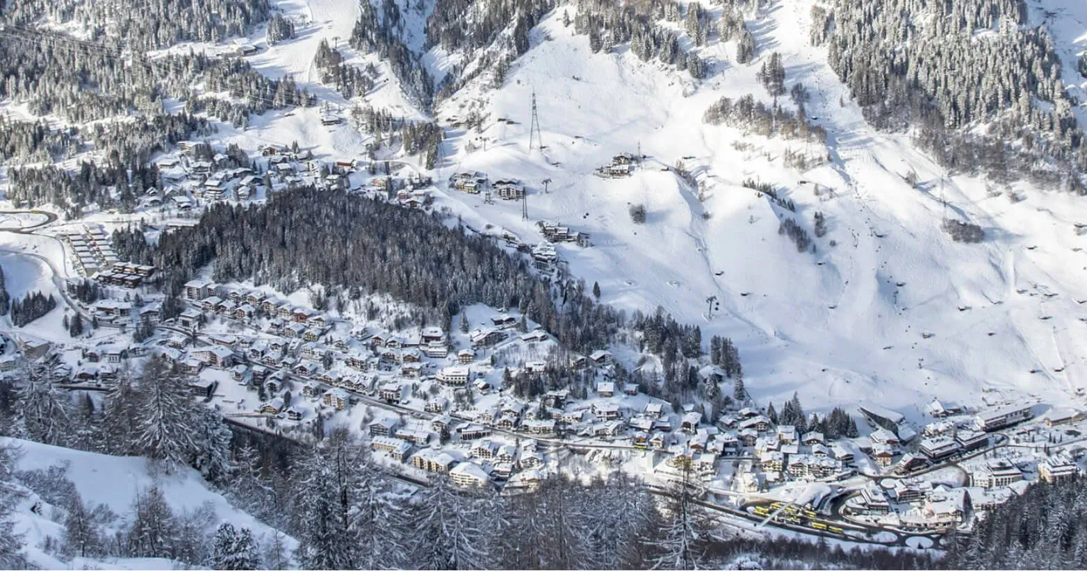 Snowy alpine village of St Anton am Arlberg nestled in ski-covered mountains and forests.