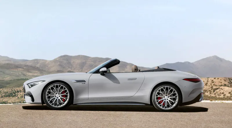 Silver Mercedes-AMG SL convertible side view, parked on road with mountains in background