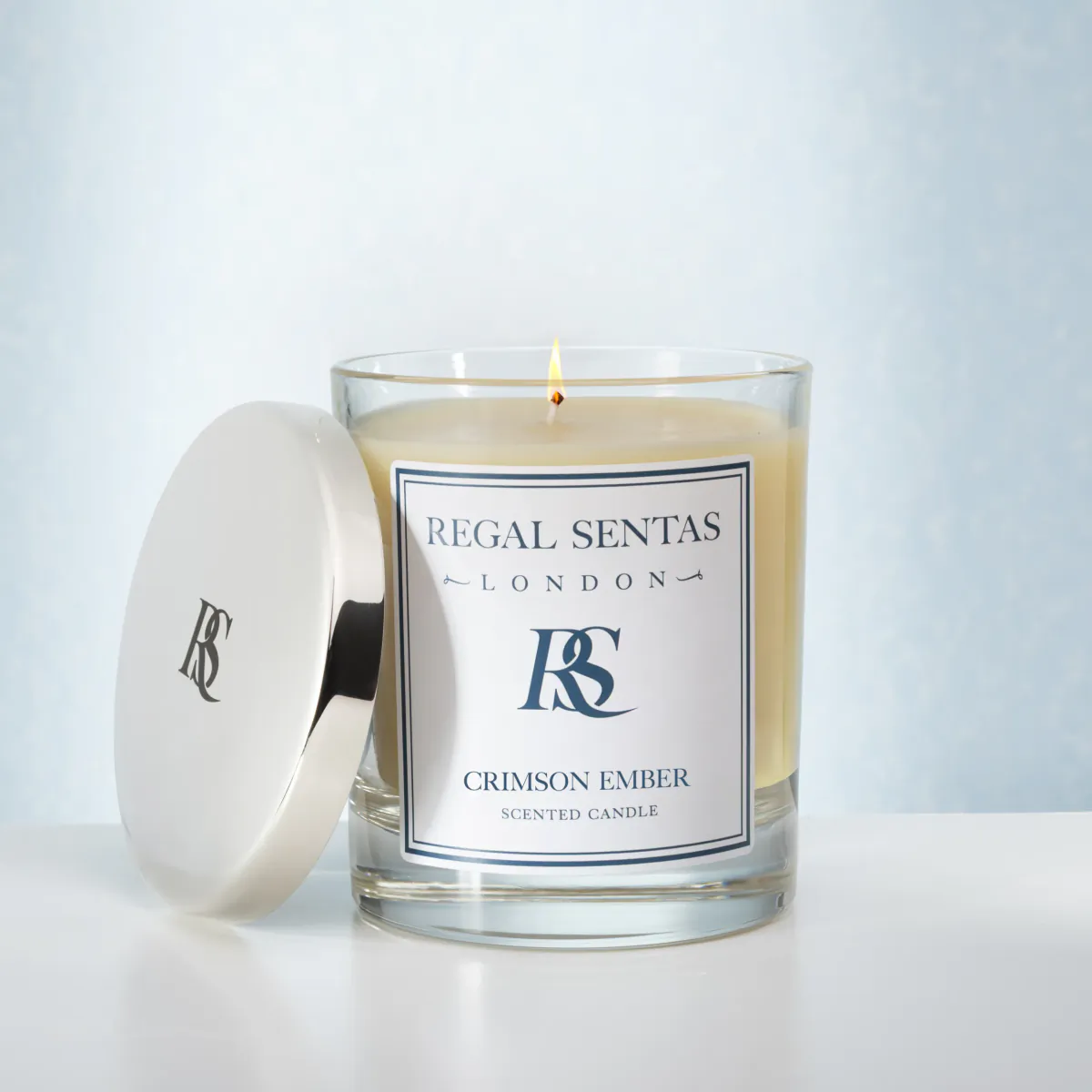 Regal Sentas Crimson Ember scented candle in glass jar with white lid, lit wick, London branding
