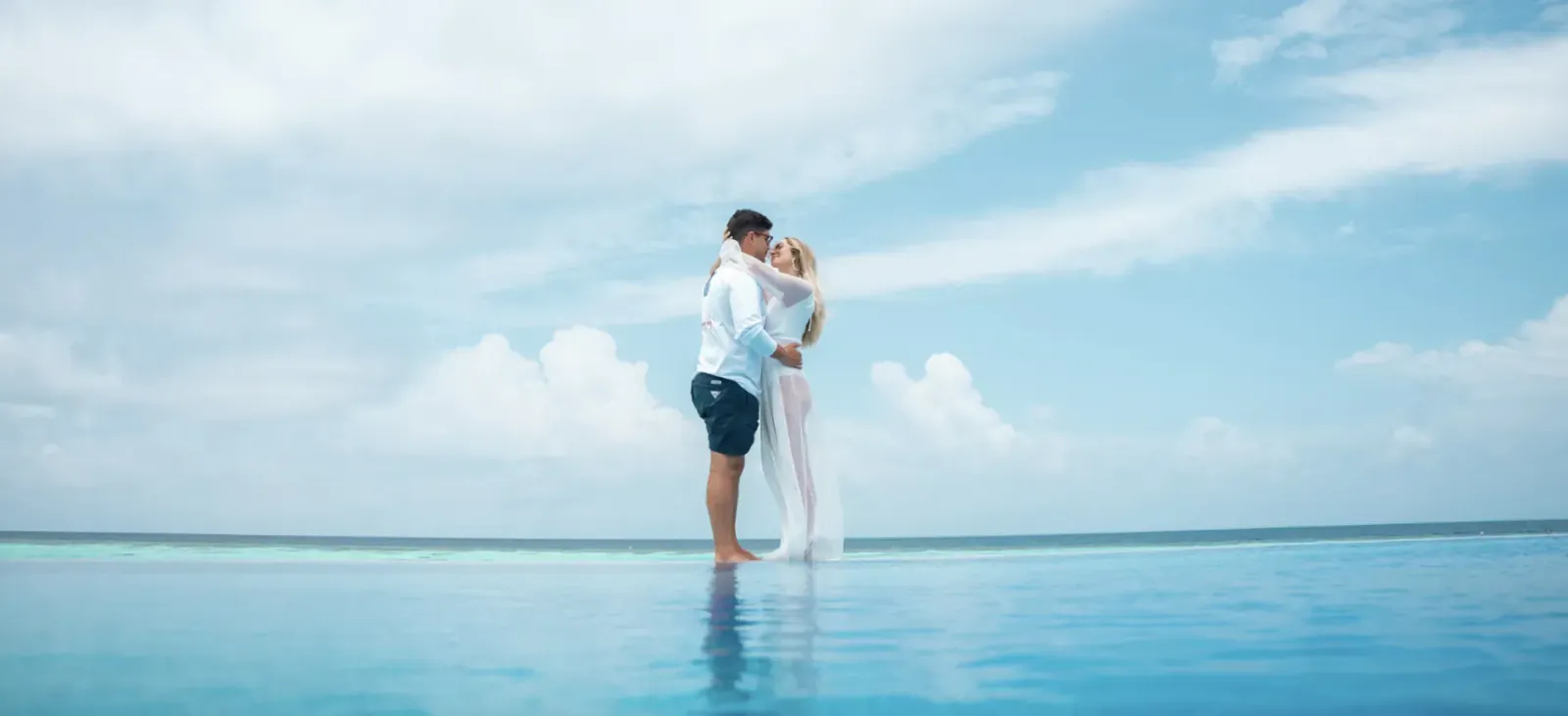 Romantic couple embracing on infinity pool edge at sunset, Lily Beach Resort, Valentine's Day