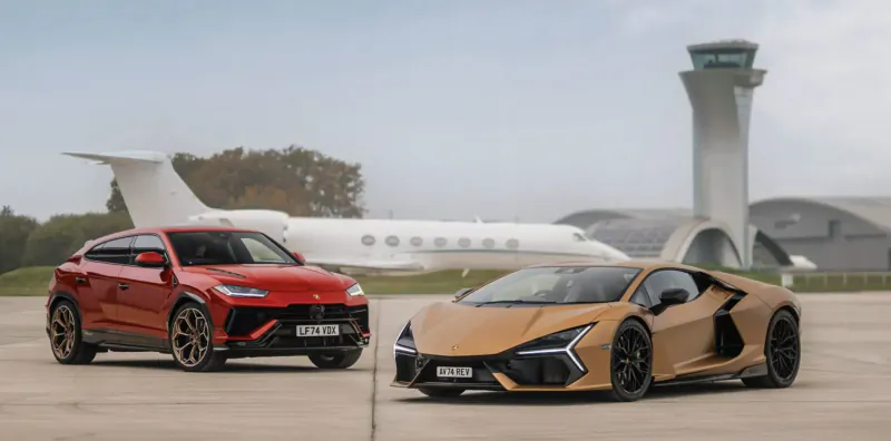 Red Lamborghini Urus and beige Lamborghini Huracan parked on tarmac near white private jet and control tower.
