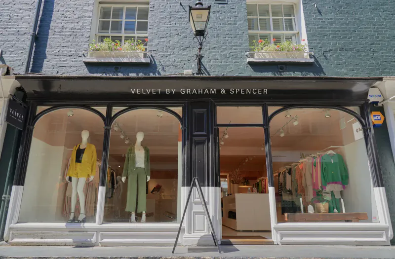 Velvet by Graham & Spencer boutique storefront on Georgian building with mannequins in colorful coats in windows