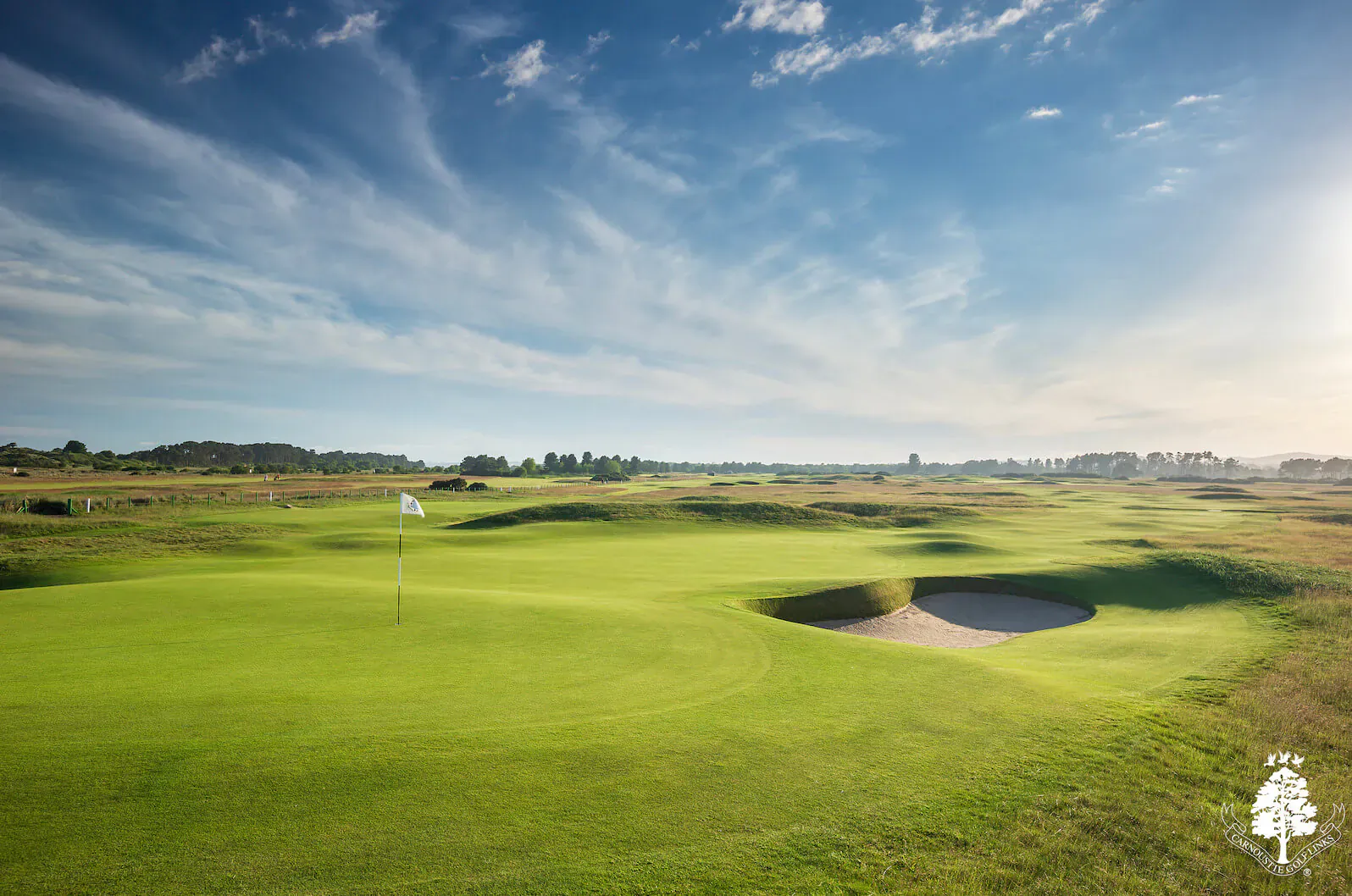 Carnoustie Links golf course with green, bunker, flag, dunes, and blue sky