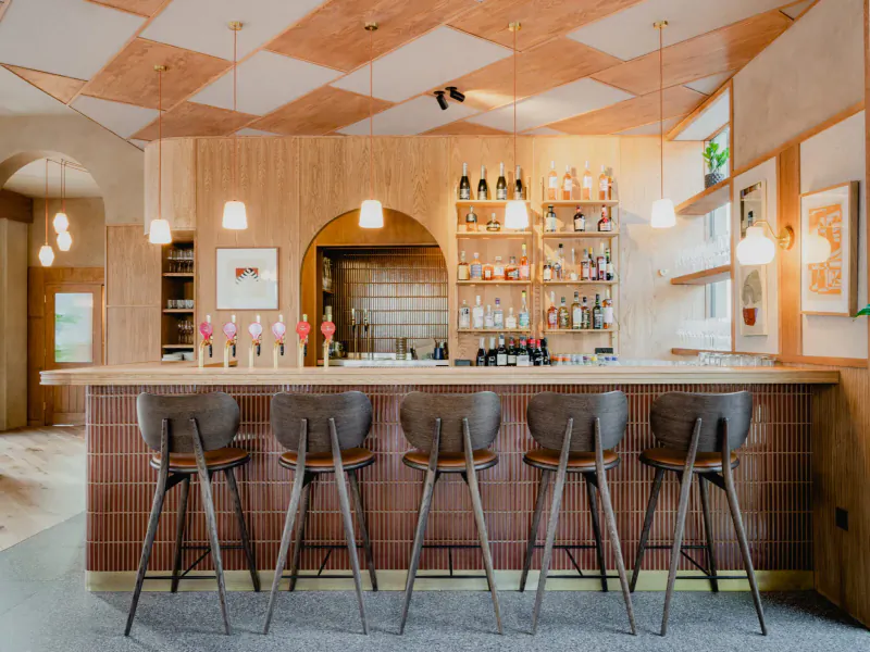 Sophisticated wooden bar at The Broadcaster with checkered ceiling, pendant lights, and lined stools