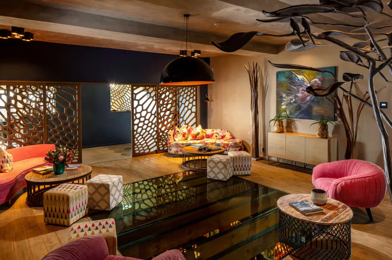 Modern Sky Villa Boutique Hotel lounge with colorful patterned sofas, glass table, potted plants, and artistic decor.