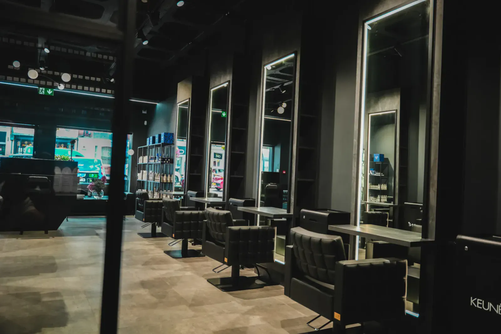 Modern black Luke Benson hair salon interior with black chairs, mirrors, and product shelves.