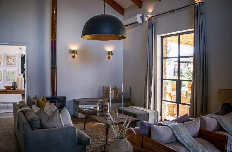Spacious modern living room in Simbavati Cederberg Ridge retreat with gray sofas, large black pendant light, and garden doors.