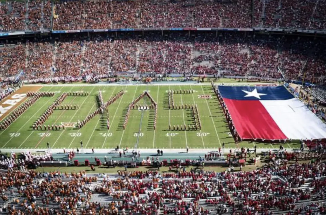 Marching band forms 'TEXAS' and holds giant Texas flag on football field in packed stadium