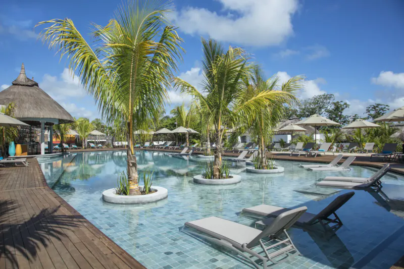 Infinity pool with palms and loungers at Anantara Iko Mauritius resort under blue skies