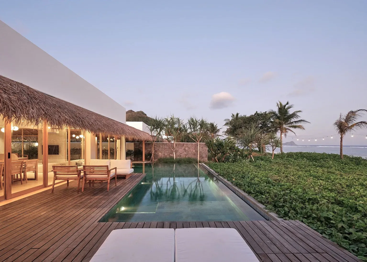 3-Bedroom Beachfront Pool Villa at Amber Lombok Beach Resort: infinity pool, wooden deck, lounge chairs, tropical garden, ocean view at dusk