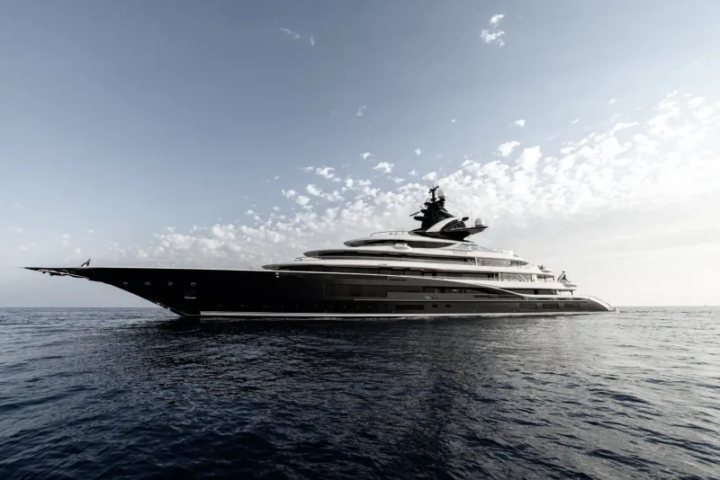 Kismet luxury yacht on the sea under cloudy sky, sleek black multi-deck design.