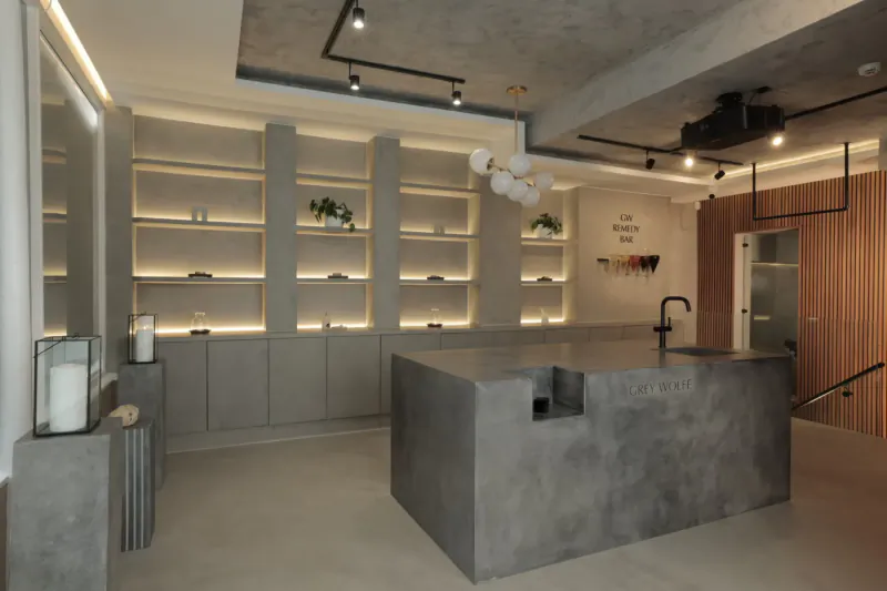Modern luxury wellness space with grey concrete central counter, wooden shelves, plants, and warm lighting