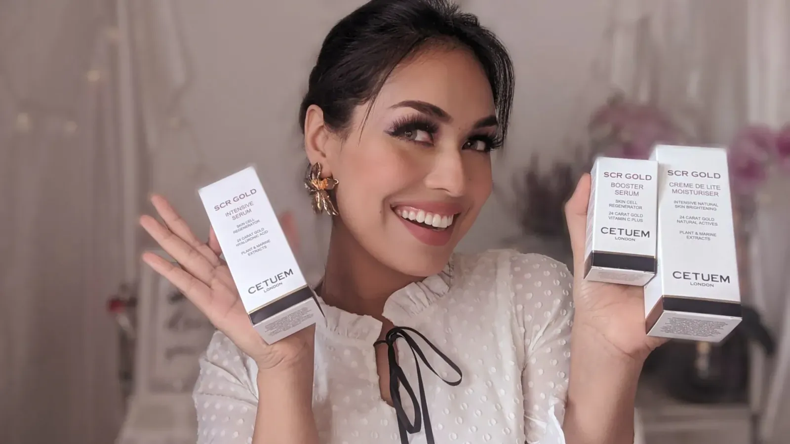 Smiling woman holding Cetuem SCR GOLD skincare boxes, white packaging with gold accents, in elegant setting