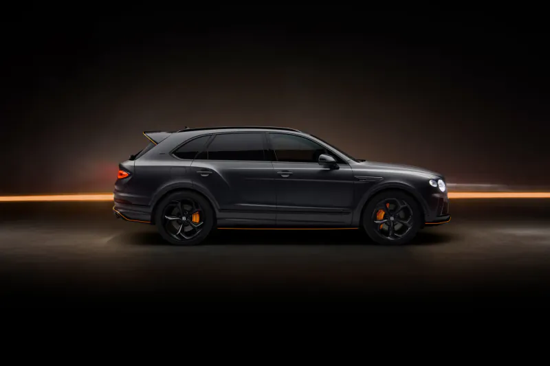 Side view of black Bentley Bentayga Wings Identifies Black Edition SUV on dark road with light trails