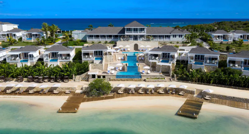 Aerial view of Hammock Cove luxury resort in Antigua with white villas, infinity pool, beach, and turquoise sea.