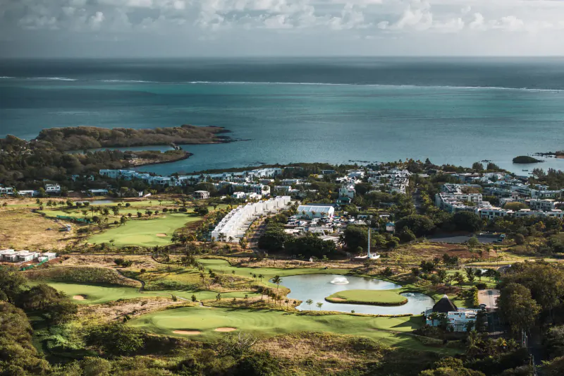 Aerial view of lush golf course with greens, ponds, and ocean horizon in Mauritius
