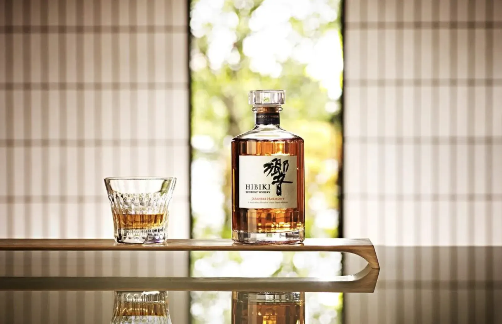 Hakuroku Japanese whisky bottle and glass of amber liquid on wooden tray by shoji window with garden view