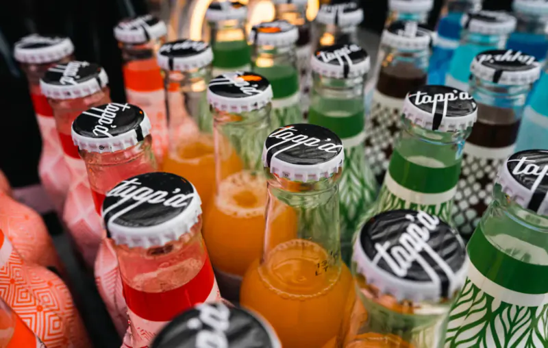 Close-up of colorful glass bottles with Topa branded caps in a luxury mobile bar display