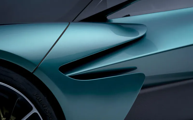 Close-up of Aston Martin Valhalla hybrid supercar's teal aerodynamic rear wheel arch and black wheel.