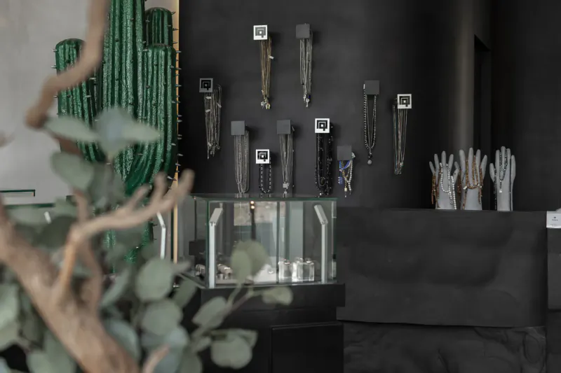 Huwa men's jewelry flagship store in Cairo: jewelry on black walls, glass display case, green cactus and eucalyptus plants foreground.