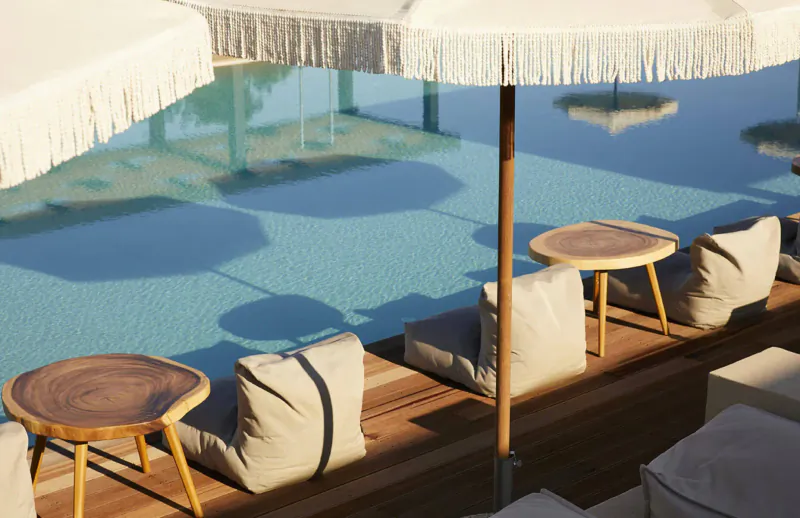 Luxury poolside lounge at Asterion Suites & Spa, Crete: wooden tables, cream cushions, white fringed umbrellas.