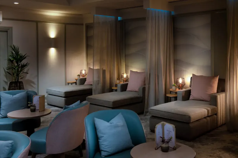 Relaxing spa lounge at Bristol Aztec Hotel with plush loungers, pink cushions, sheer curtains, and soft lighting.