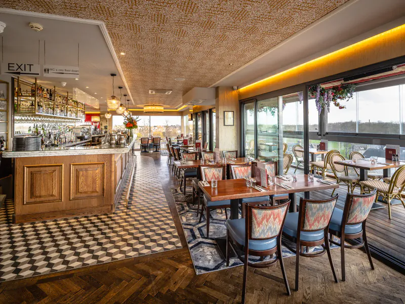 Elegant Gallery restaurant interior at Varsity Hotel & Spa with wooden bar, checkered floors, tables, and large windows overlooking views